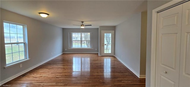 empty room with ceiling fan, dark hardwood / wood-style flooring, and a wealth of natural light