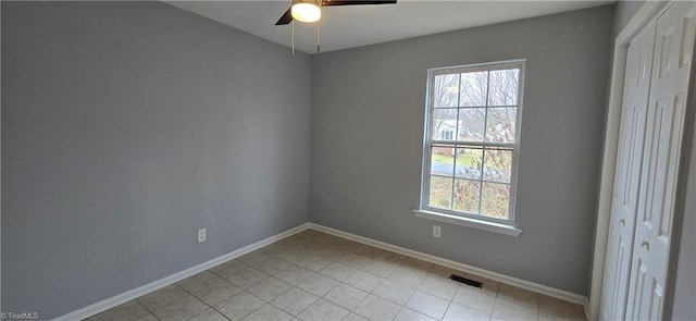 tiled empty room with ceiling fan and a healthy amount of sunlight