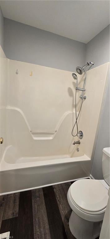 bathroom with shower / bathing tub combination, hardwood / wood-style floors, and toilet