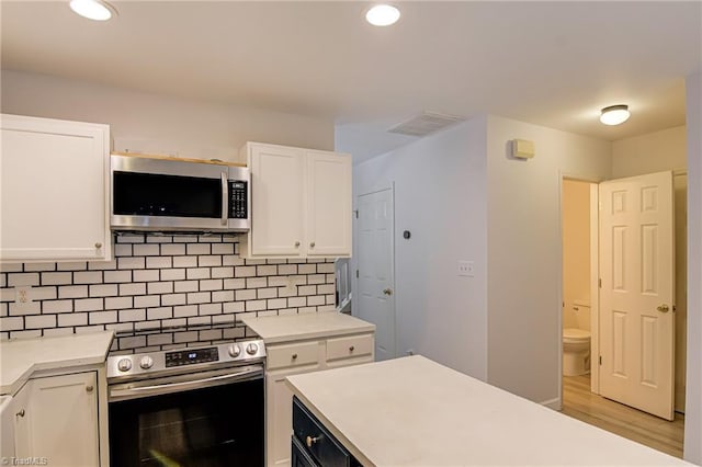 5430 Strasburg Dr, Greensboro, NC 27407 - kitchen with stainless steel appliances, white cabinets, light wood finished floors, tasteful backsplash, and light countertops