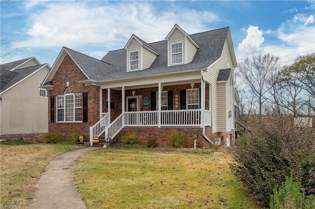 cape cod home featuring covered porch and a front lawn