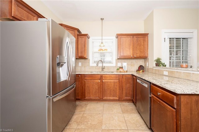 kitchen with sink, stainless steel appliances, tasteful backsplash, light stone counters, and pendant lighting