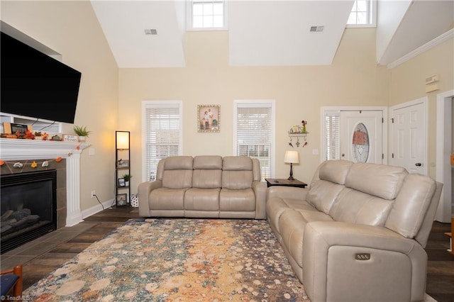 living room featuring dark hardwood / wood-style flooring, high vaulted ceiling, and a tiled fireplace