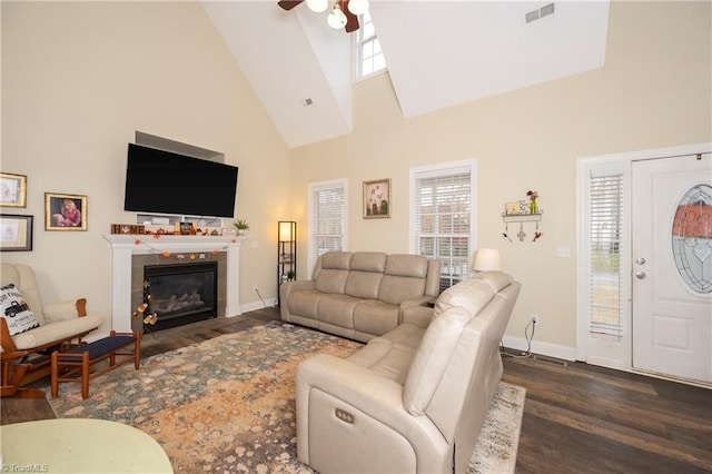 living room featuring a wealth of natural light, a fireplace, high vaulted ceiling, and dark wood-type flooring