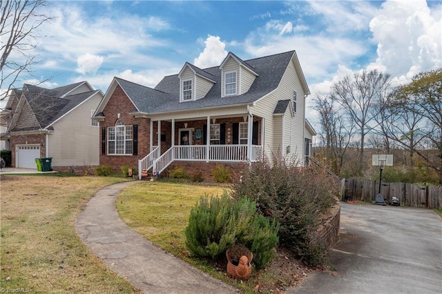 cape cod-style house featuring a garage, covered porch, and a front yard