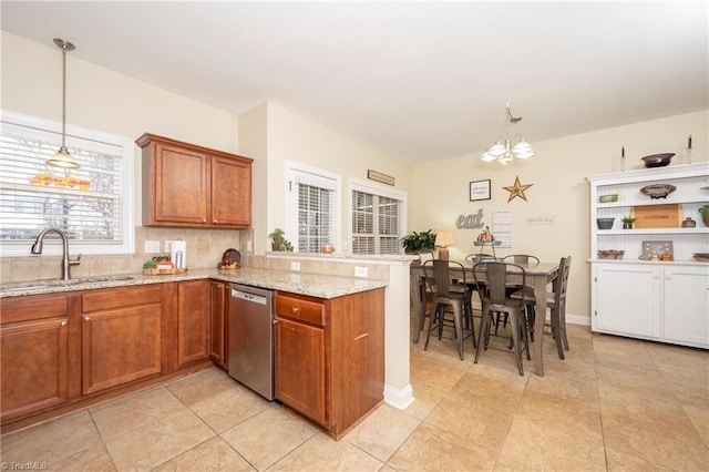 kitchen with light stone countertops, sink, an inviting chandelier, stainless steel dishwasher, and pendant lighting