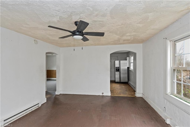 unfurnished room with ceiling fan, a baseboard heating unit, and a textured ceiling