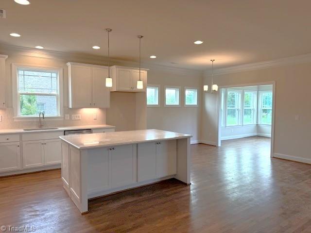 7607 Valhalla Way Lot 20, Greensboro, NC 27409 - kitchen featuring crown molding, a center island, a sink, and white cabinetry