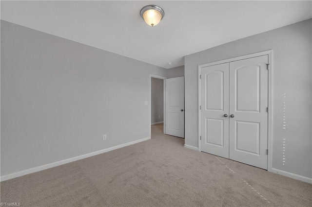 unfurnished bedroom with a closet and light colored carpet