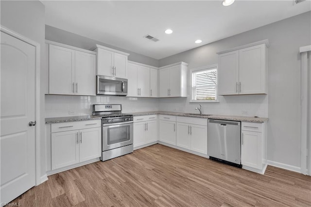 kitchen featuring sink, white cabinets, stainless steel appliances, and light wood-type flooring