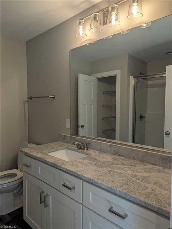 full bath with toilet, a stall shower, and vanity