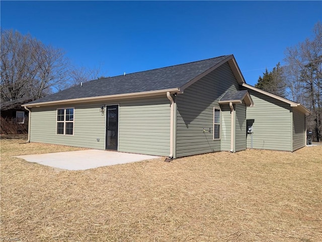 back of house with a patio, a lawn, and roof with shingles