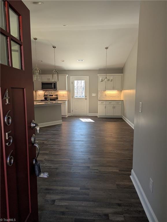 interior space with white cabinetry, dark wood-type flooring, tasteful backsplash, and appliances with stainless steel finishes