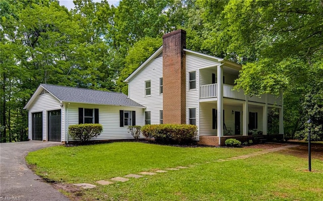 neoclassical / greek revival house with a balcony, a front lawn, a chimney, asphalt driveway, and a garage