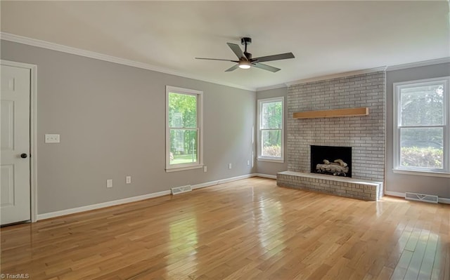 unfurnished living room with a ceiling fan, crown molding, light wood-type flooring, baseboards, and a brick fireplace