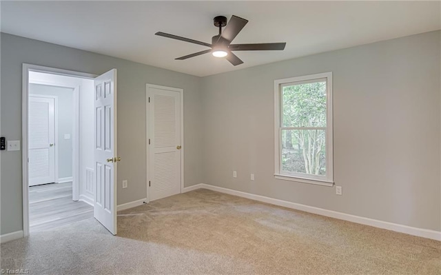 unfurnished room featuring light carpet, a ceiling fan, and baseboards