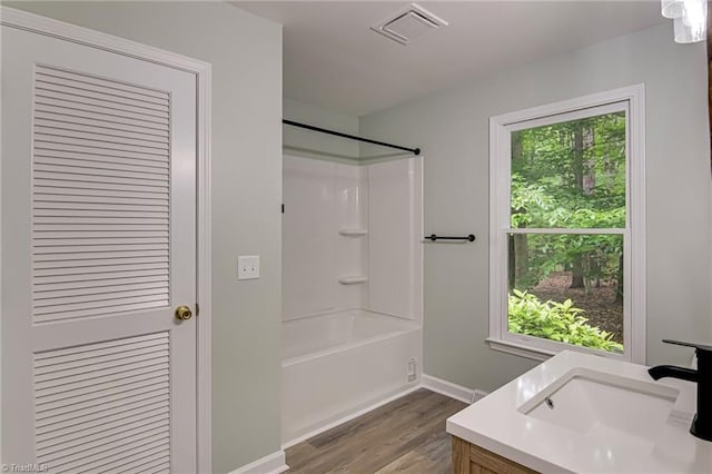 bathroom featuring wood finished floors, tub / shower combination, baseboards, and vanity
