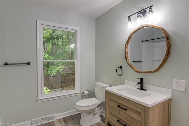 bathroom with wood finished floors, vanity, toilet, and baseboards