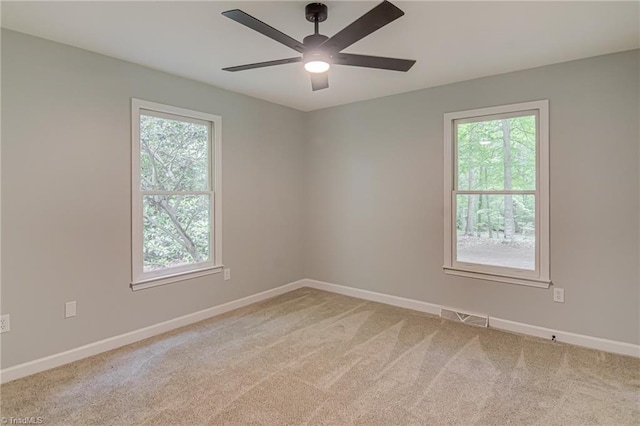 spare room featuring healthy amount of natural light, carpet, a ceiling fan, and baseboards