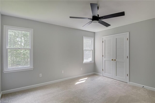 unfurnished bedroom featuring multiple windows, baseboards, carpet flooring, and a closet
