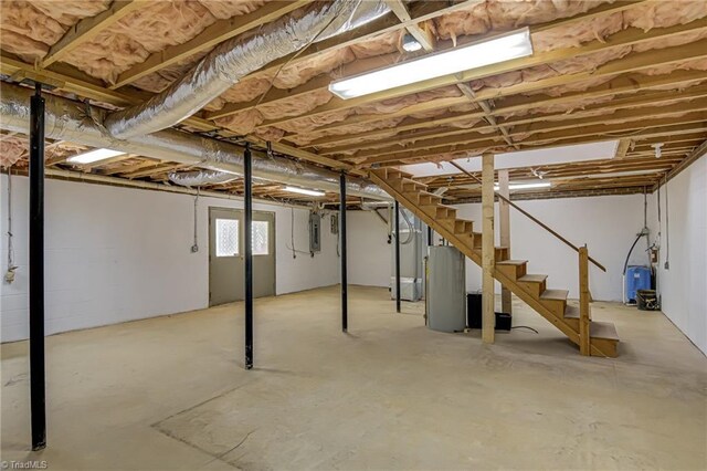 basement featuring stairs, a water pressure tank, and electric panel