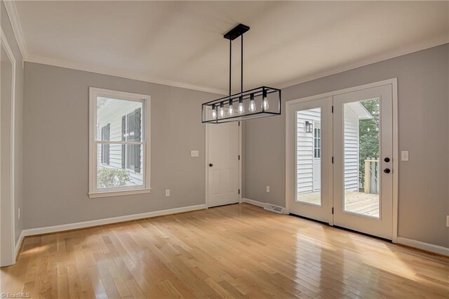 unfurnished dining area with crown molding, light wood-style flooring, and baseboards