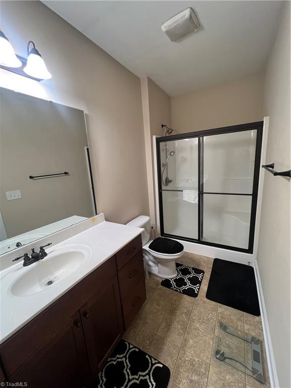 bathroom featuring toilet, walk in shower, and vanity