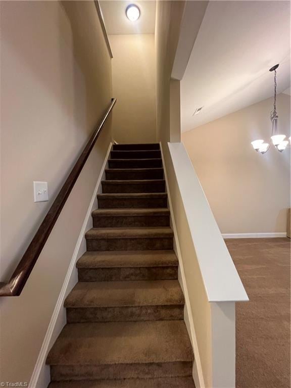 stairs with an inviting chandelier and carpet flooring