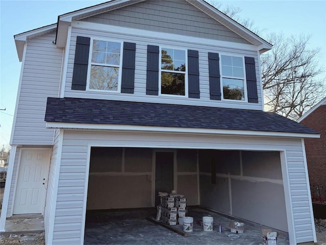 view of front of home with a garage and roof with shingles