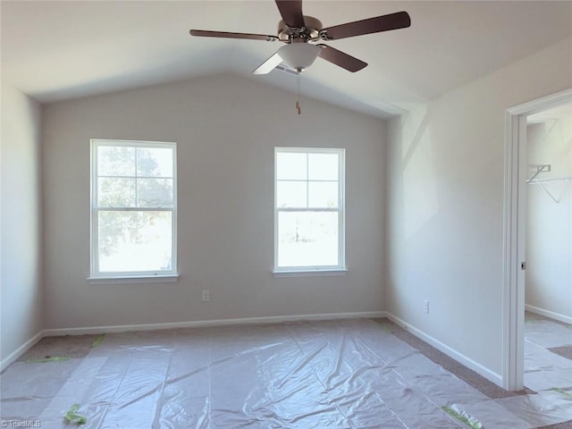 spare room with a ceiling fan, vaulted ceiling, plenty of natural light, and baseboards