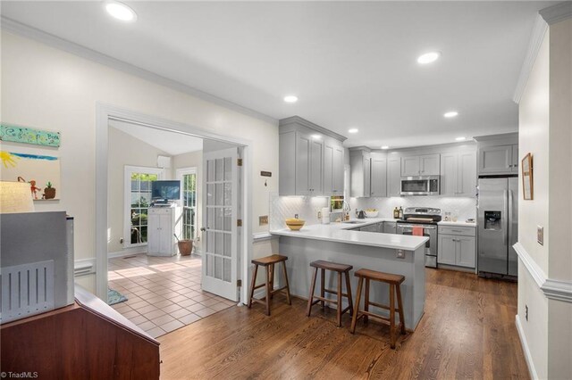 4105 Waldenbrook Rd, Greensboro, NC 27407 - kitchen featuring a peninsula, a sink, decorative backsplash, gray cabinetry, and appliances with stainless steel finishes
