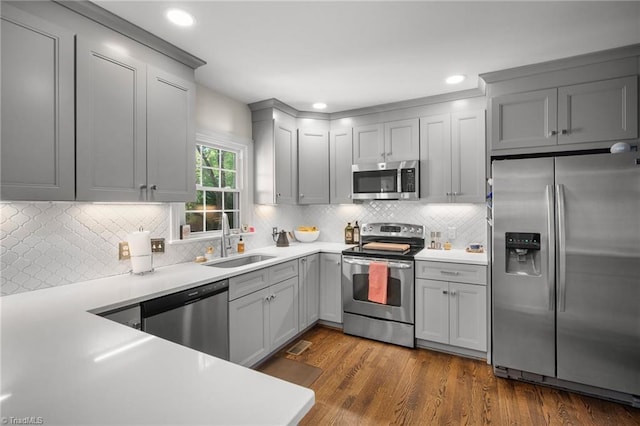 4105 Waldenbrook Rd, Greensboro, NC 27407 - kitchen with tasteful backsplash, a sink, gray cabinets, dark wood finished floors, and appliances with stainless steel finishes