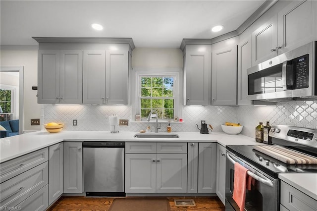 4105 Waldenbrook Rd, Greensboro, NC 27407 - kitchen with a sink, decorative backsplash, gray cabinetry, light countertops, and appliances with stainless steel finishes