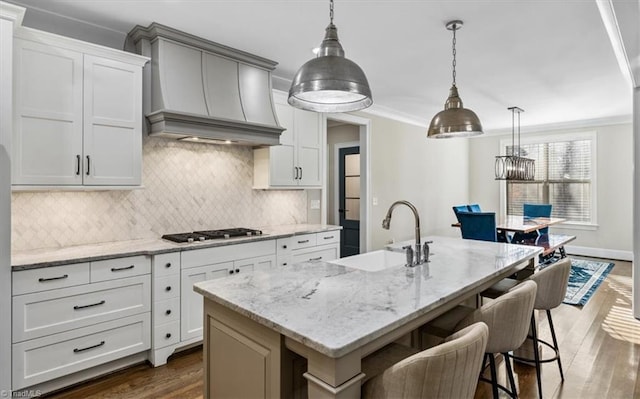 kitchen with custom range hood, dark hardwood / wood-style floors, a kitchen island with sink, and sink