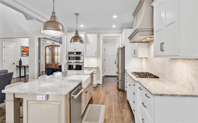 kitchen with light stone countertops, premium range hood, stainless steel appliances, hanging light fixtures, and a large island