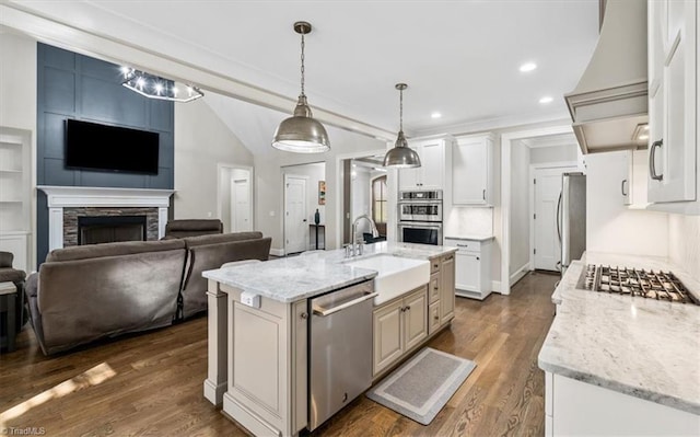 kitchen with a kitchen island with sink, white cabinets, light stone countertops, and appliances with stainless steel finishes