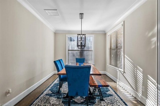 dining area with dark hardwood / wood-style flooring, ornamental molding, and a chandelier