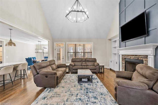 living room with a fireplace, hardwood / wood-style floors, a chandelier, and high vaulted ceiling