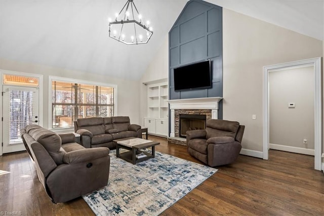 living room with a fireplace, dark hardwood / wood-style flooring, high vaulted ceiling, and a chandelier