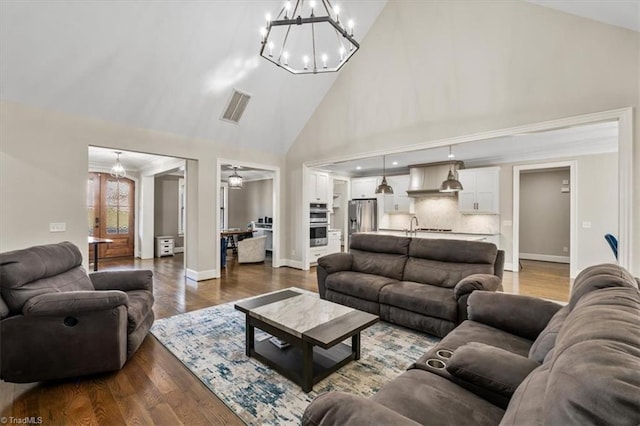 living room featuring hardwood / wood-style floors, high vaulted ceiling, and a notable chandelier