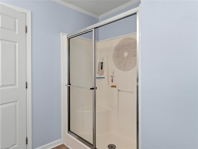 bathroom with a shower stall, a textured ceiling, and crown molding