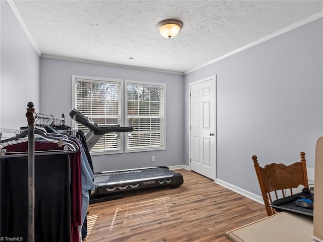 workout room with crown molding, a textured ceiling, baseboards, and wood finished floors