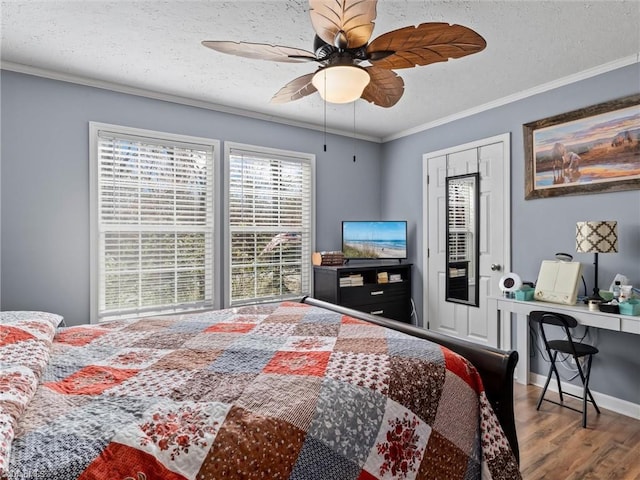 bedroom featuring ornamental molding, a ceiling fan, a textured ceiling, wood finished floors, and baseboards