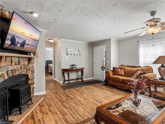 living area featuring baseboards, a ceiling fan, ornamental molding, wood finished floors, and a textured ceiling