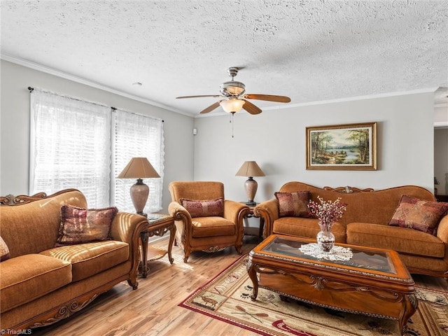 living area with light wood finished floors, ceiling fan, a textured ceiling, and crown molding