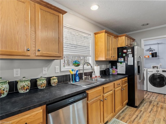 kitchen with crown molding, appliances with stainless steel finishes, light wood-style floors, a sink, and separate washer and dryer