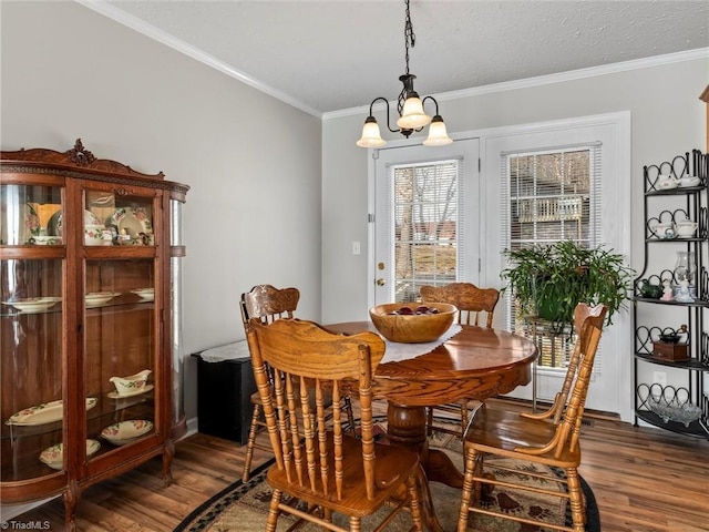 dining area featuring a textured ceiling, a notable chandelier, crown molding, and wood finished floors