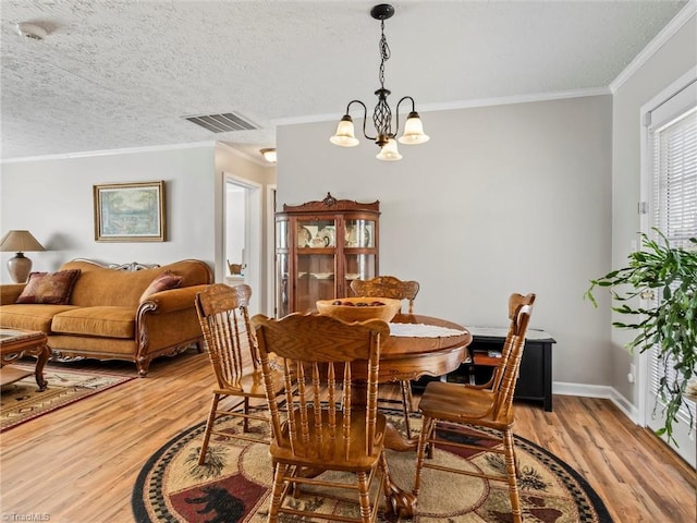 dining room featuring visible vents, crown molding, a textured ceiling, and light wood finished floors