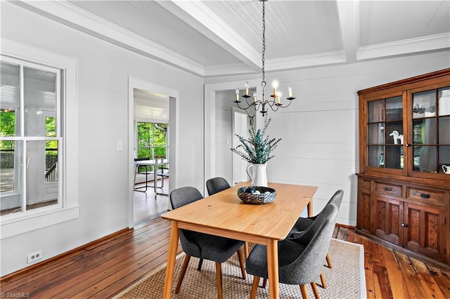 dining space featuring dark wood finished floors, a chandelier, beamed ceiling, and ornamental molding