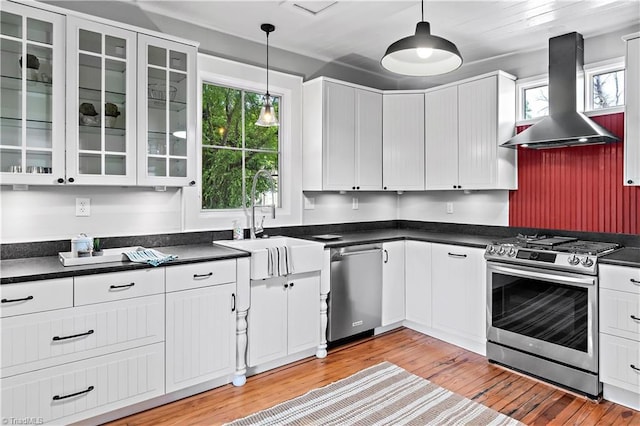 kitchen featuring appliances with stainless steel finishes, island exhaust hood, dark countertops, and light wood-style floors